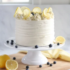 Sliced simple and moist Lemon Blueberry Cake with cream cheese frosting on a stand.