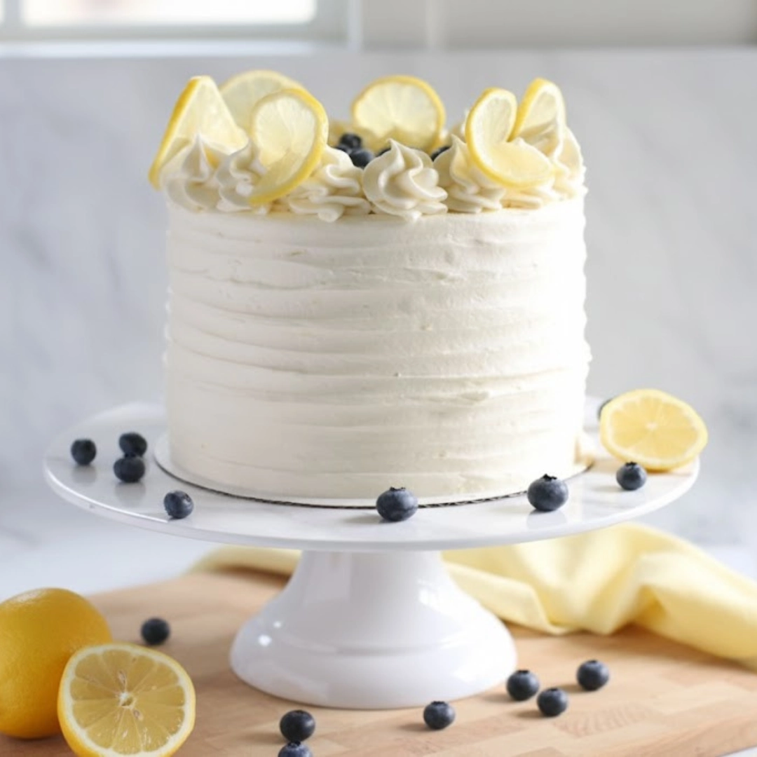 Sliced simple and moist Lemon Blueberry Cake with cream cheese frosting on a stand.