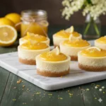 A close-up view of perfectly baked and chilled Mini Lemon Cheesecakes topped with fresh lemon zest and whipped cream