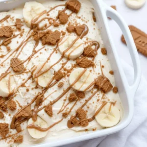 Layered glass dish of Biscoff Banana Pudding topped with crushed speculoos cookies