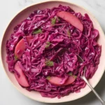 Vibrant bowl of finished Cozy German Cabbage (Rotkohl) topped with fresh herbs, ready to be served as a hearty side dish.
