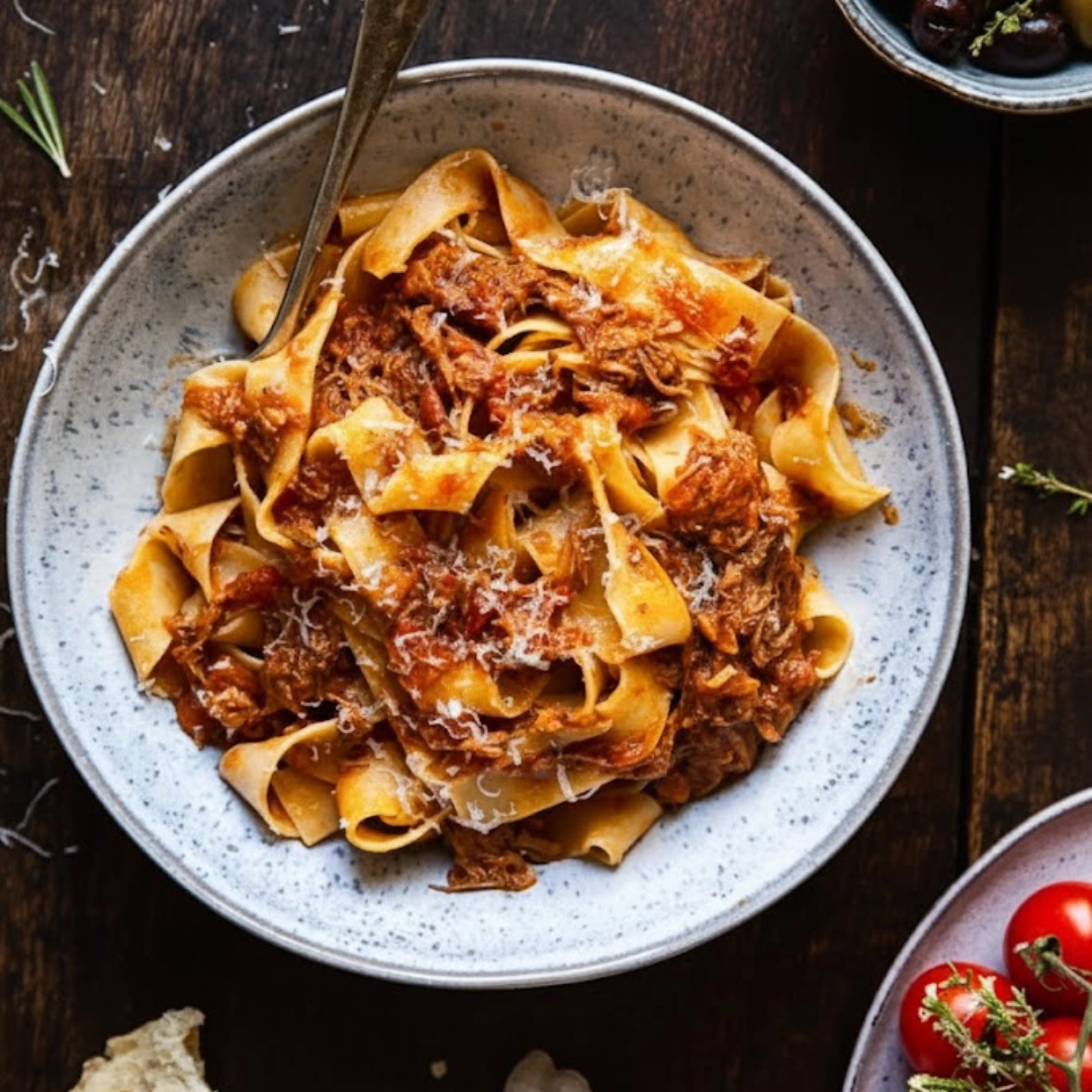 A bowl of rich Slow Cooker Italian Beef Ragu served over pappardelle pasta and topped with fresh herbs.