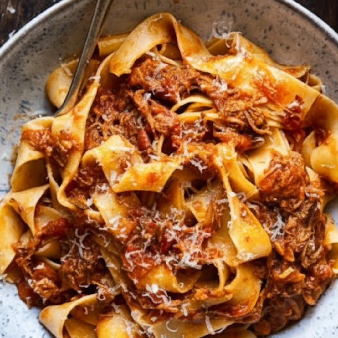 A bowl of rich Slow Cooker Italian Beef Ragu served over pappardelle pasta and topped with fresh herbs.