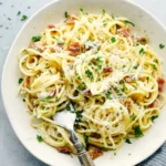 A large bowl of beautiful, glossy Creamy Bacon Carbonara Pasta topped with crispy turkey bacon and fresh black pepper.