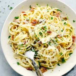 A large bowl of beautiful, glossy Creamy Bacon Carbonara Pasta topped with crispy turkey bacon and fresh black pepper.